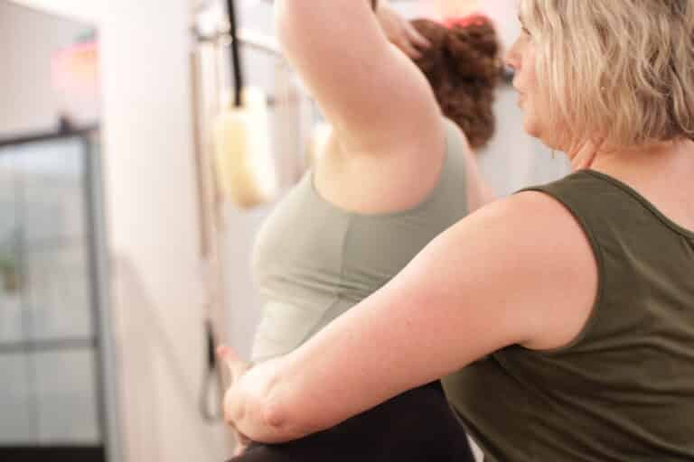 private Pilates instructor teaching client how to align her body during her workout